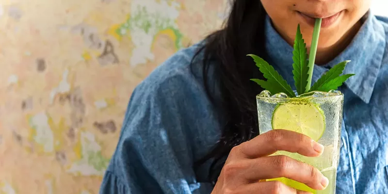 Young Woman drinking a THC-infused drink with a straw, the image features a cannabis leaf.