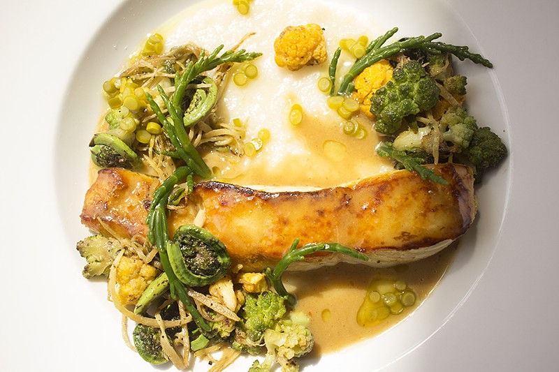 Lacquered halibut is served with miso butter, jasmine congee, fiddle heads, confit garlic scapes, sea beans, cauliflower and broccoli. - MABEL SUEN