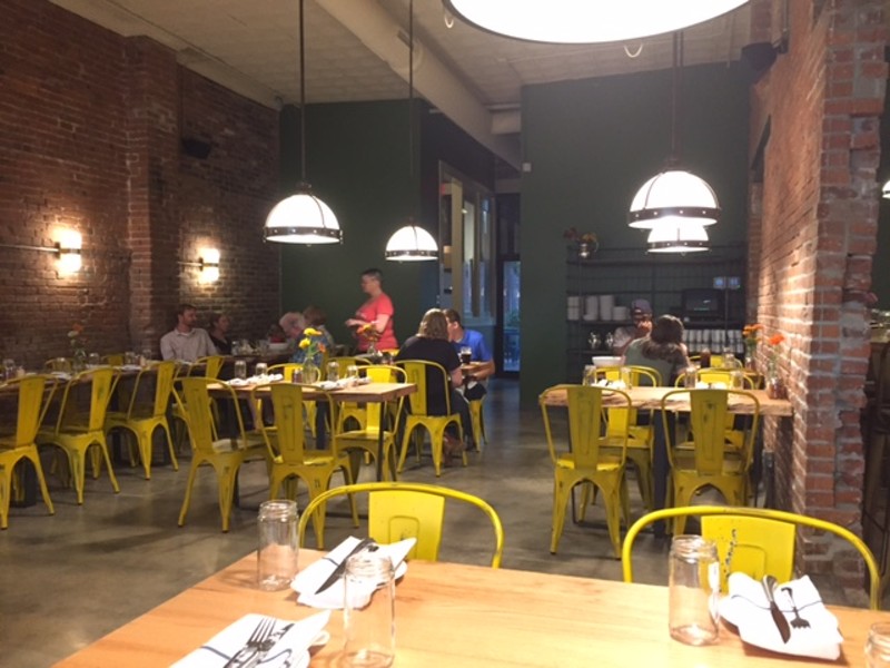 Brick walls line the restaurant, with yellow chairs for a splash of color. - PHOTO BY SARAH FENSKE