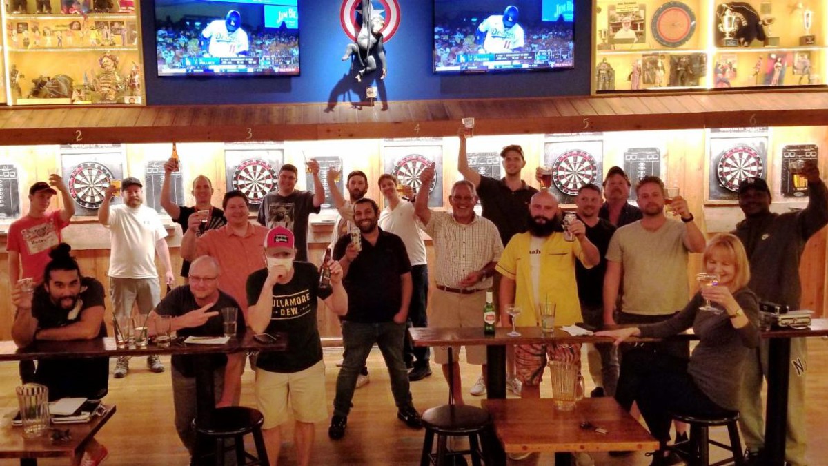 The Blueberry Hill Dart League stands in front of the dart board