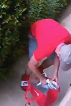 Security footage shows a porch pirate as he puts a white Amazon package into a DoorDash bag.