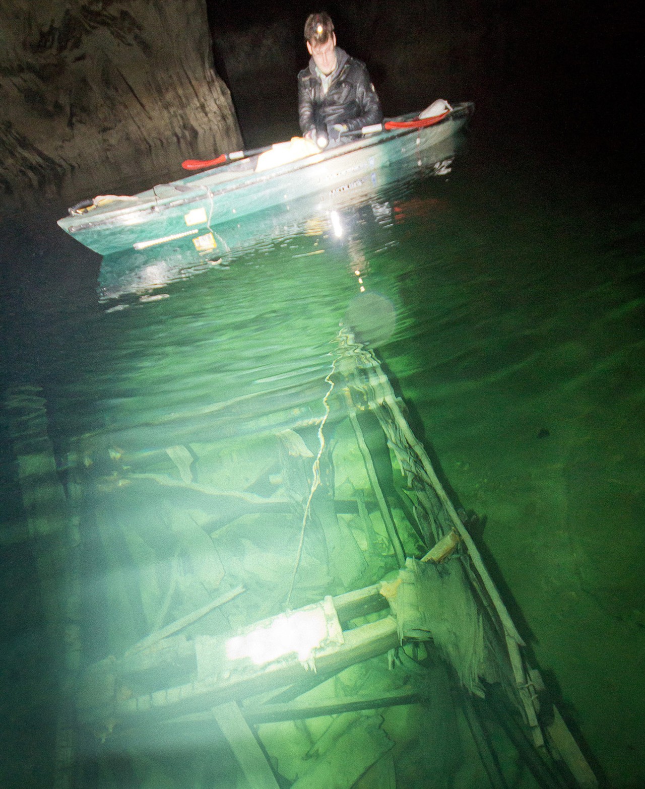 A participant in an underground kayak tour examines what was once a car wash inside the abandoned and flooded PPG silica mine.