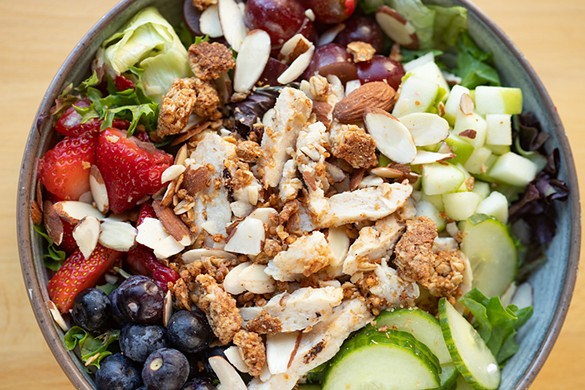 Honey apple salad with antibiotic-free chicken, apples, strawberries, grapes, blueberries, cucumbers, almonds, granola and honey-apple vinaigrette.